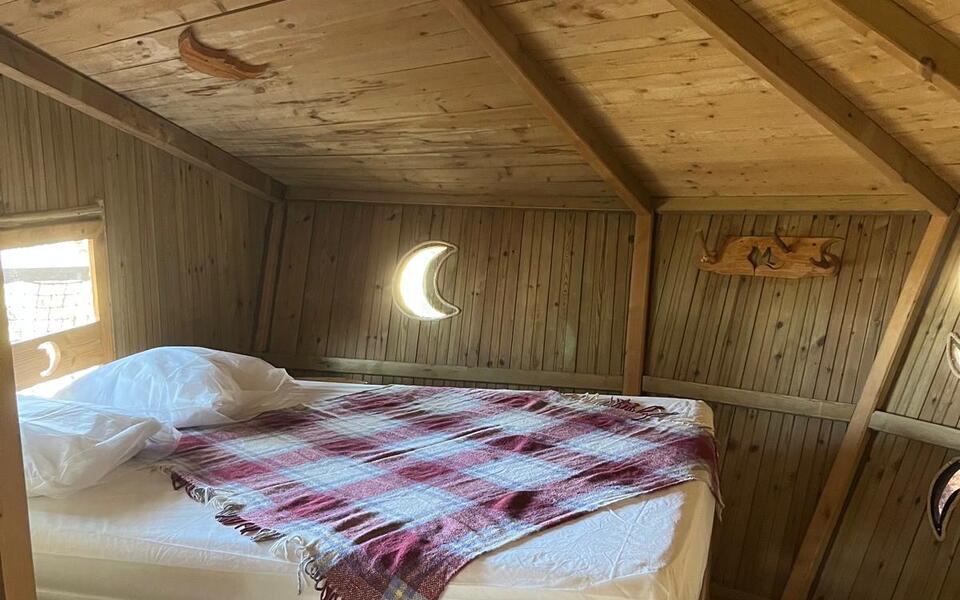 Intérieur en bois d'une chambre de cabane avec un lit double et une décoration en forme de lune